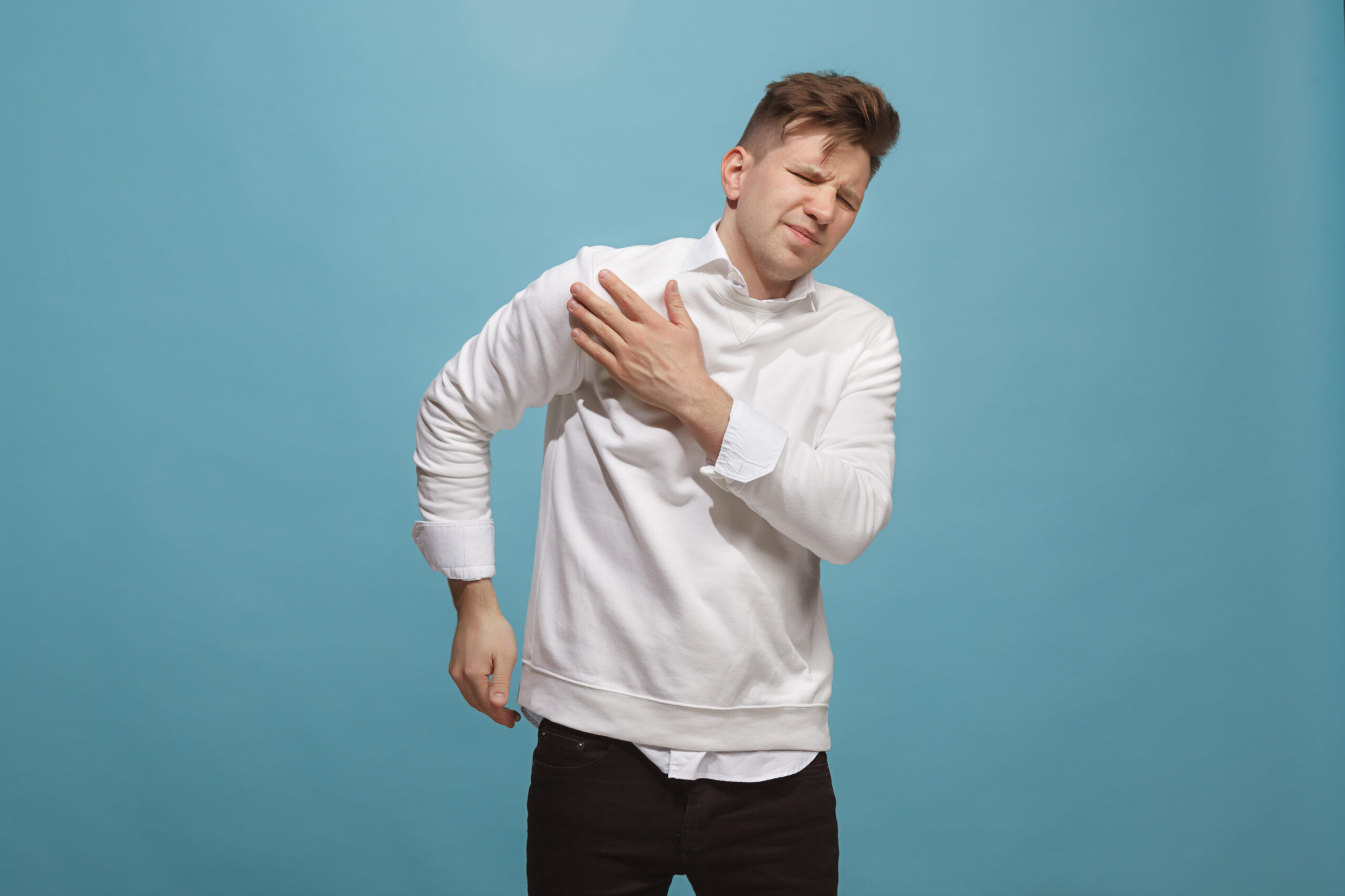 Pain concept. Beautiful male portrait isolated on studio backgroud. Young emotional surprised man looking at camera.Human emotions, facial expression concept. man overwhelmed with pain in shoulder